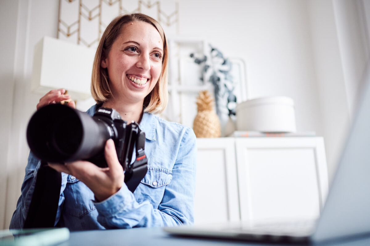Food Fotografin Cornelia sitzt mit Kamera in der Hand vor dem Laptop