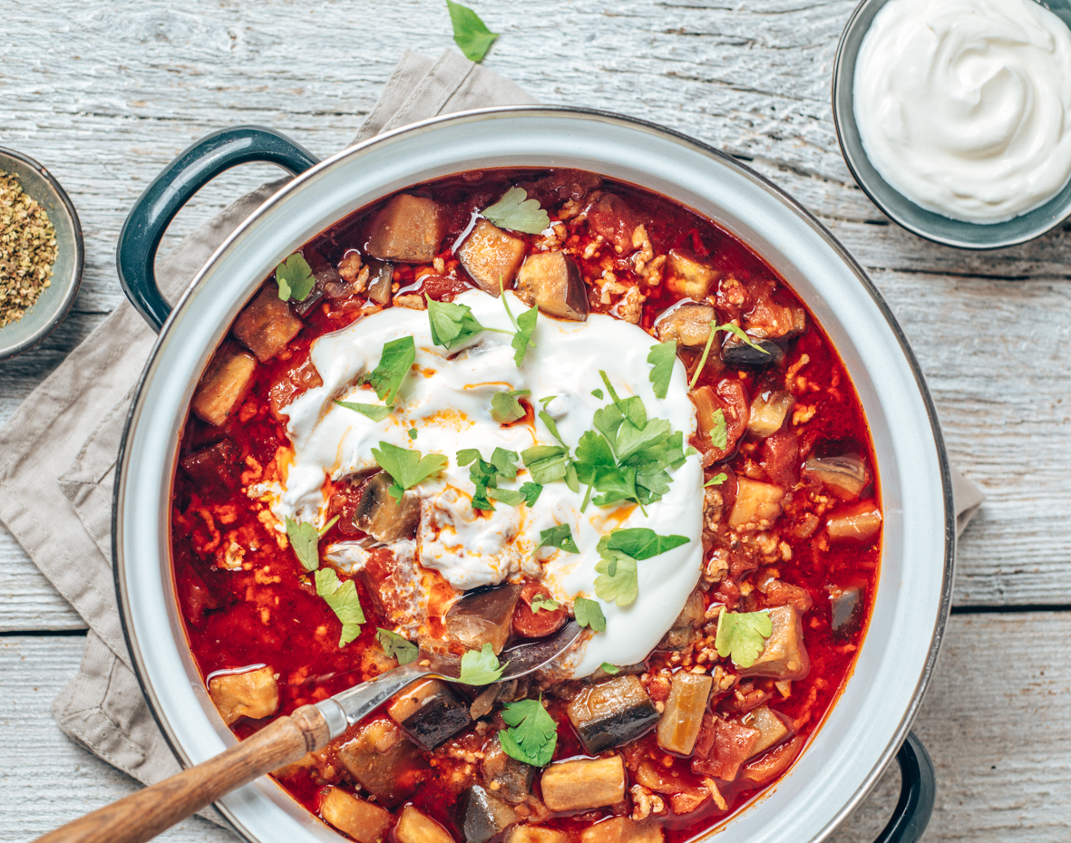 Food Fotografie von einem Moussaka auf hellem Hintergrund mit einer Sauerrahmschüssel