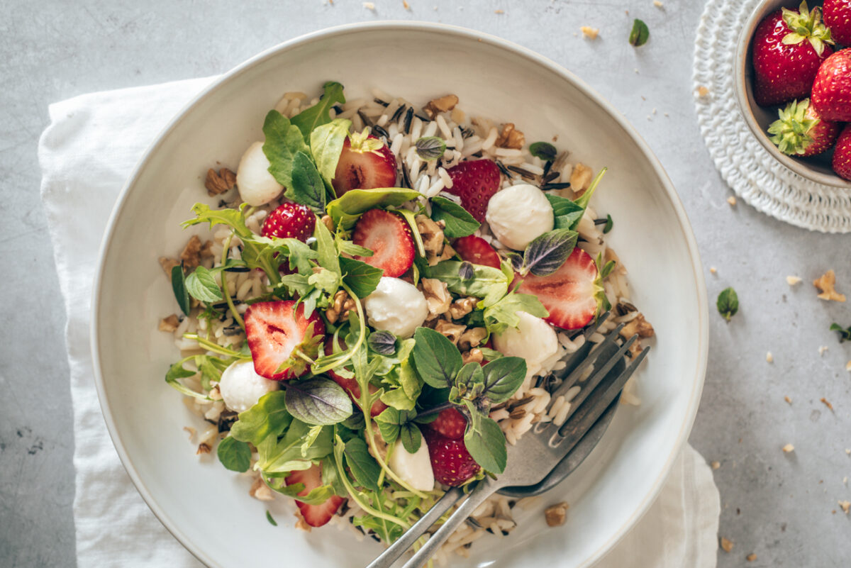 Food Foto Erdbeer-Wildreis-Salat im Querformat auf weißem Teller und auf einer weißen Serviette