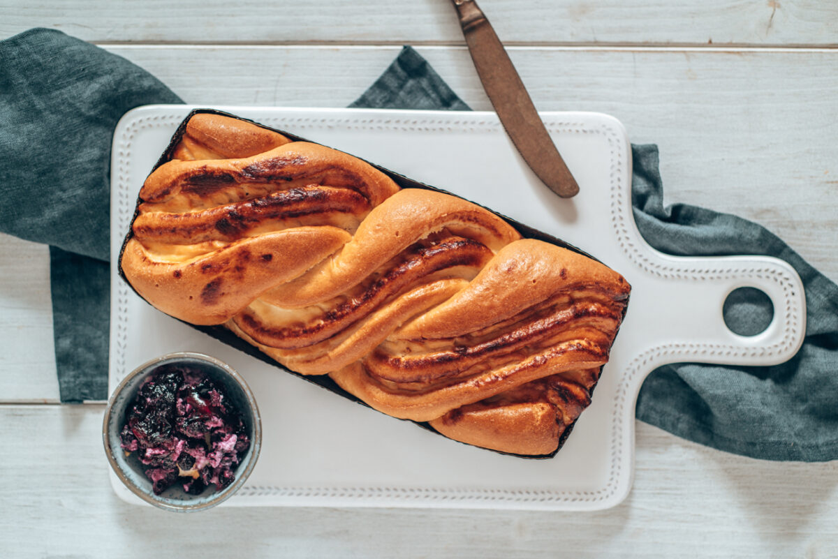 Topfenstrudel auf weißem Keramikbrett mit dunkelblauem Tuch