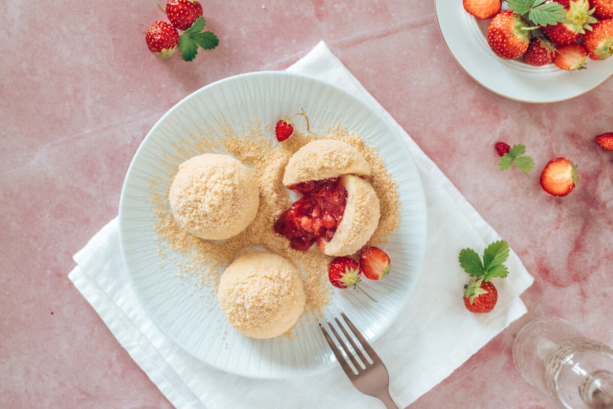 Erdbeerknödel auf rosa Untergrund und weißem Teller