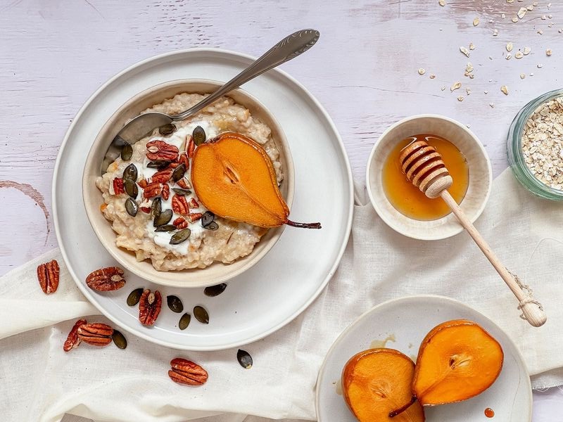 Porridge mit Birnen und Trockenfrüchten vor weißem Hintergrund