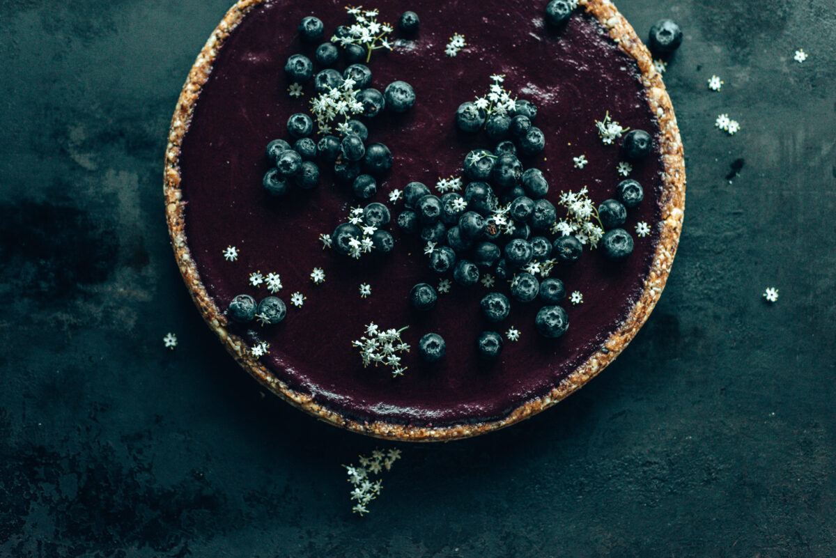 Heidelbeer-Tarte auf dunklem Untergrund mit Holunderblüten