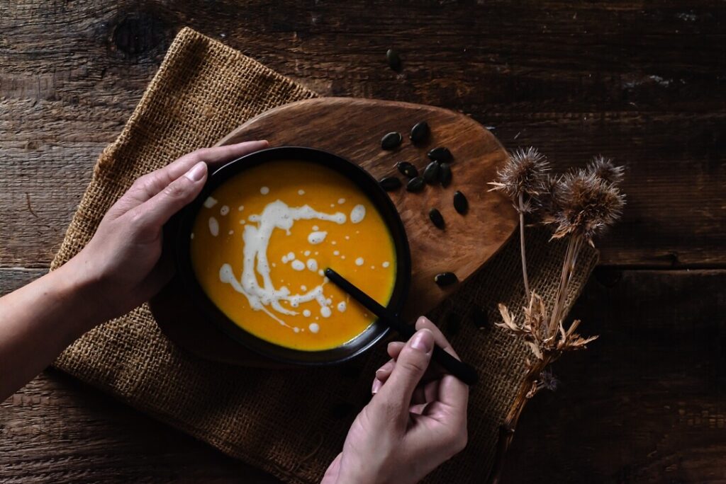 Kürbiscreme-Suppe rustikal mit Holz und Disteln